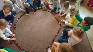 dzieci układają kasztany w koło na dywanie