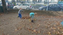 dzieci grabiące liście w ogrodzie