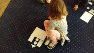 Dzieci układają na dywanie zamki z figur geometrycznych