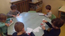 Dzieci przy stoliku wykonują bałwanki na kartkach