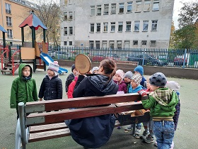 zdjęcie dzieci i nauczycielki w ogrodzie przedszkolnym słcuhających ciekawostek o drzewie