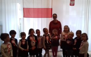 Zdjęcie grupy Tygrysów na tle flagi polski z okazji udziału w akcji "Szkoła do hymnu"