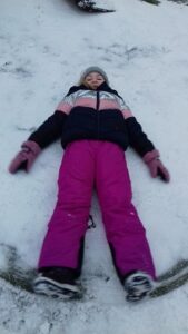 zdjęcie dziecka robiącego aniołka na śniegu
