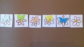 Na brązowym tle znajduję się sześć narysowanych kwiatków, na pięciu z nich leżą motyle.