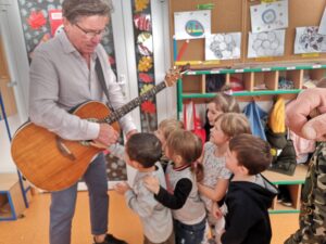 dzieci ustawione w rzędzie dotykają gitary