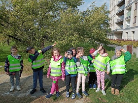 Dzieci stoją na dworze. Są ubrane w zielone odblaskowe kamizelka. Pozują do zdjęcia
