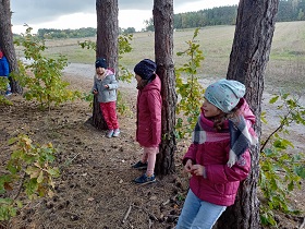 Trzy dziewczynki stoją oparte plecami o drzewa