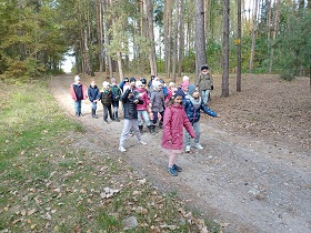 Dzieci stoją w grupie w lesie, przygotowują się do biegu.