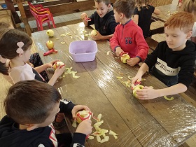 Dzieci obierają jabłka obieraczkami