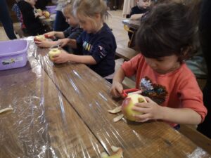 dzieci obierają jabłka przy stole