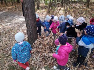 dzieci otaczają drzewo liśćmi
