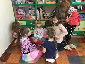 Na podłodze siedzi grupka dzieci i ze sobą rozmawia
