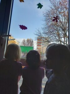 Dzieci stoją przy oknie i obserwują to co dzieje się za oknem.