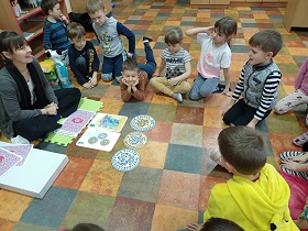 Dzieci obserwują leżące na podłodze obrazki monet i banknotów oraz modele monet.