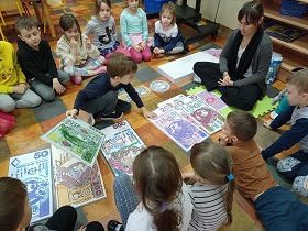 Dzieci obserwują chłopca, który układa modele banknotów w określonej kolejności. Na podłodze leżą modele banknotów 50,200,500,100,20,10.