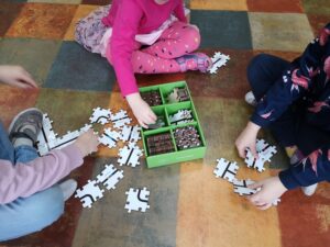 troje dzieci układają puzzle