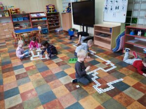 dzieci układają puzzle na podłodze w sali