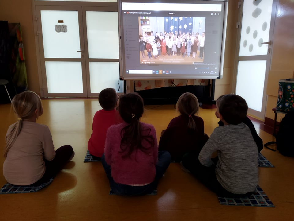 grupa dzieci siedzi przed monitorem