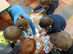 Dzieci układają puzzle i puszczają mini roboty po trasach.