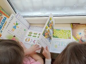 Dwie dziewczynki oglądają książki szkolne z zadaniami.