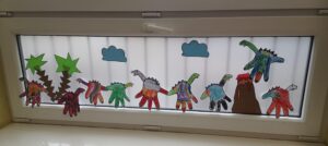 na oknie naklejone papierowe dinozaury