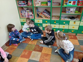 Dzieci siedzą w kółku i przekazują sobie wiadomość szepcząc do ucha. Chłopiec nachyla się do chłopca. Reszta dzieci wyczekuje.