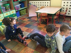 Dzieci siedzą na podłodze i stykają się plecami.