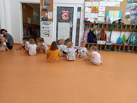 Dzieci siedzą na podłodze, stopy oparte są na podłodze.