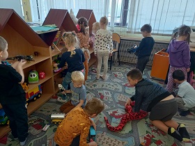Dzieci bawią się w kąciku na dywanie zabawkami. 
