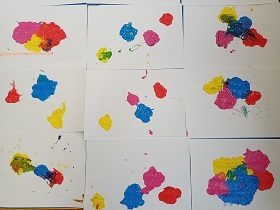 Prace plastyczne dzieci. Kartki białe A4 z kleksami farby żółtej, niebieskiej, różowej i czerwonej. 