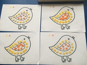 Prace plastyczne wykonane przez dzieci: kontury ptaków wyklejone żółtą i pomarańczową plasteliną.