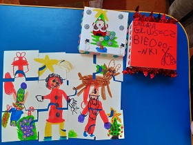 Na stole leżą ułożone puzzle. Na obrazku narysowana jest dwójka dzieci, renifer, choineczka, prezenty i gwiazda betlejemska.