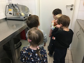 Grupka dzieci, ogląda przedszkolną kuchnię. W tle widać krajalnicę.