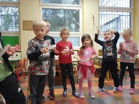 Dzieci stoją obok siebie i trzymają kartoniki w dłoniach. 