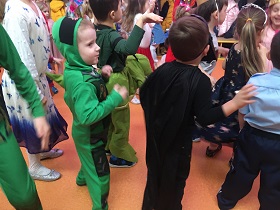 Dwóch chłopców tańczy. Jeden ma zielony strój, a drugi czarny.