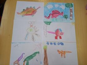 Na stole leży sześć prac z rysunkami dinozaurów narysowanych przez dzieci.
