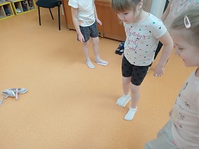 Dziewczynki pocierają stopami w skarpetkach, po woreczkach gimnastycznych