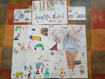 Na podłodze znajdują się rysunki dzieci przedstawiające różne rodzaje dymów. Rysunki wykonane są flamastrami. 