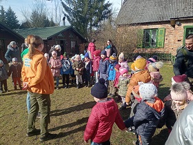 Dzieci wraz z dorosłymi stoją na dworze w kurtkach. 
