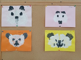 Na tablicy wiszą cztery prace dzieci. Przedstawiają pandy, namalowane białą i czarną farbą. 