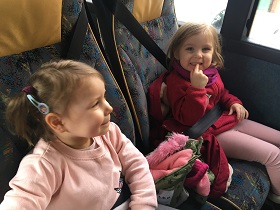 dwie uśmiechnięte dziewczynki siedzące w autokarze
