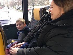 uśmiechnięty chłopiec z mamą siedzą na fotelach w autokarze.