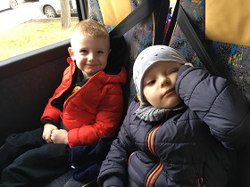 dwóch uśmiechniętych chłopców siedzących w autokarze