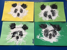 Cztery prace leżą na niebieskim tle. Przedstawiają pandę wykonaną białą i czarną farbą.