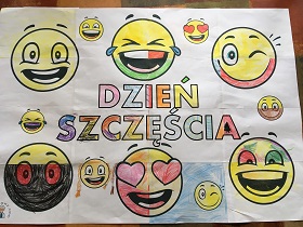 Plakat pokolorowany przez dzieci. Na plakacie znajdują się uśmiechnięte emotikony oraz napis dzień szczęścia.