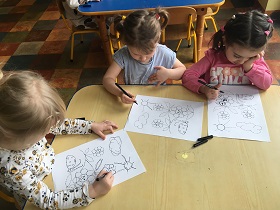 3 dziewczynki rysują po śladzie wiosenny rysunek.