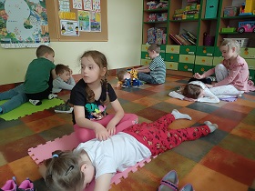 Dzieci pracują w parach na podłodze. Jedno dziecko z pary leży na macie, drugie znajduję się przy nim i go masuje. 