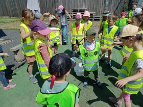 Dzieci w odblaskowych kamizelkach trzymają kijki do robienia baniek. 