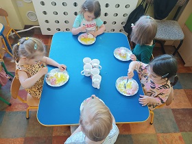Pięcioro dzieci siedzi przy stoliku i jedzą galaretkę i lody