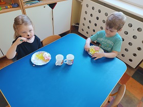 Dwoje dzieci siedzi przy stoliku i jedzą galaretkę i lody